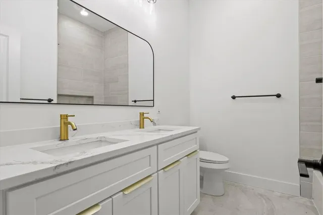 a bathroom with a granite countertop sink a toilet and a mirror