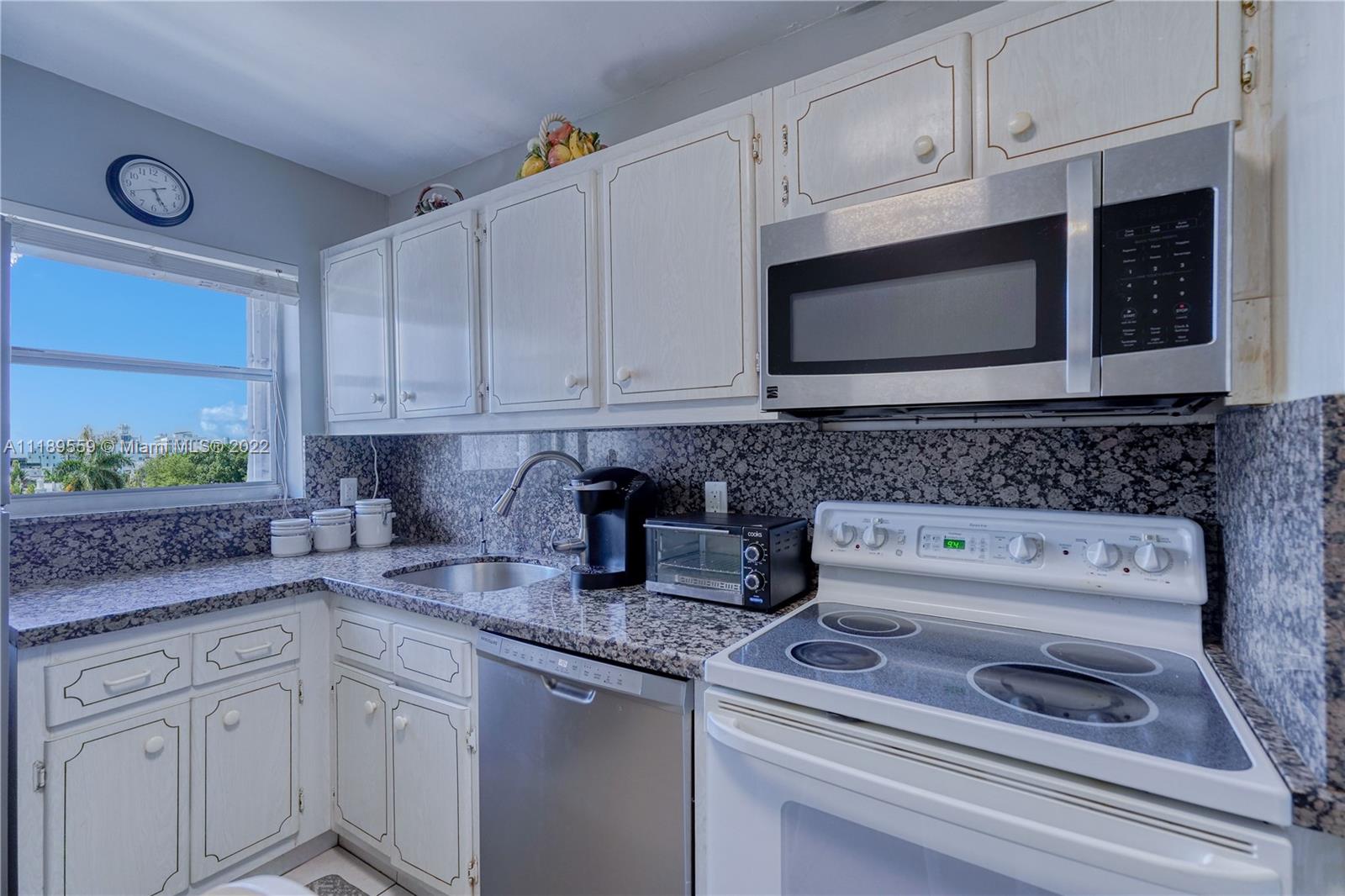 245 18th Street, Unit 602 Miami Beach, FL 33139 - Photo 19 of 40 a kitchen with granite countertop white cabinets and a stove