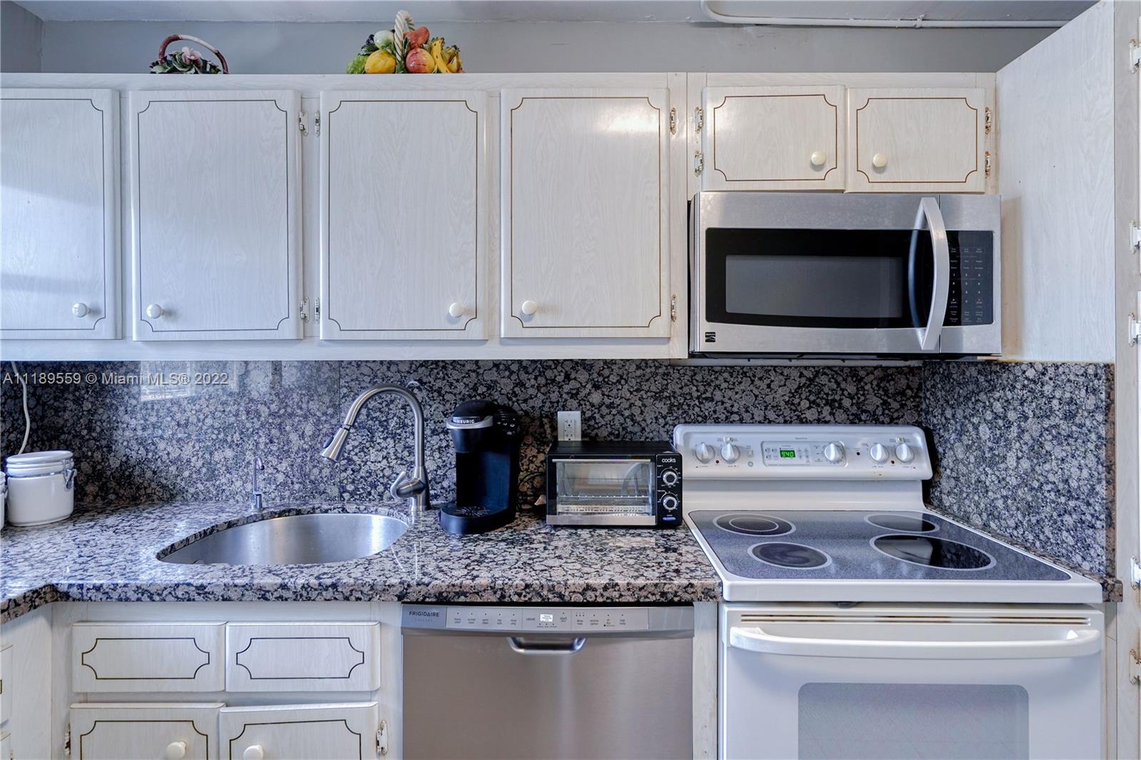 245 18th Street, Unit 602 Miami Beach, FL 33139 - Photo 20 of 40 a kitchen with granite countertop white cabinets and a stove