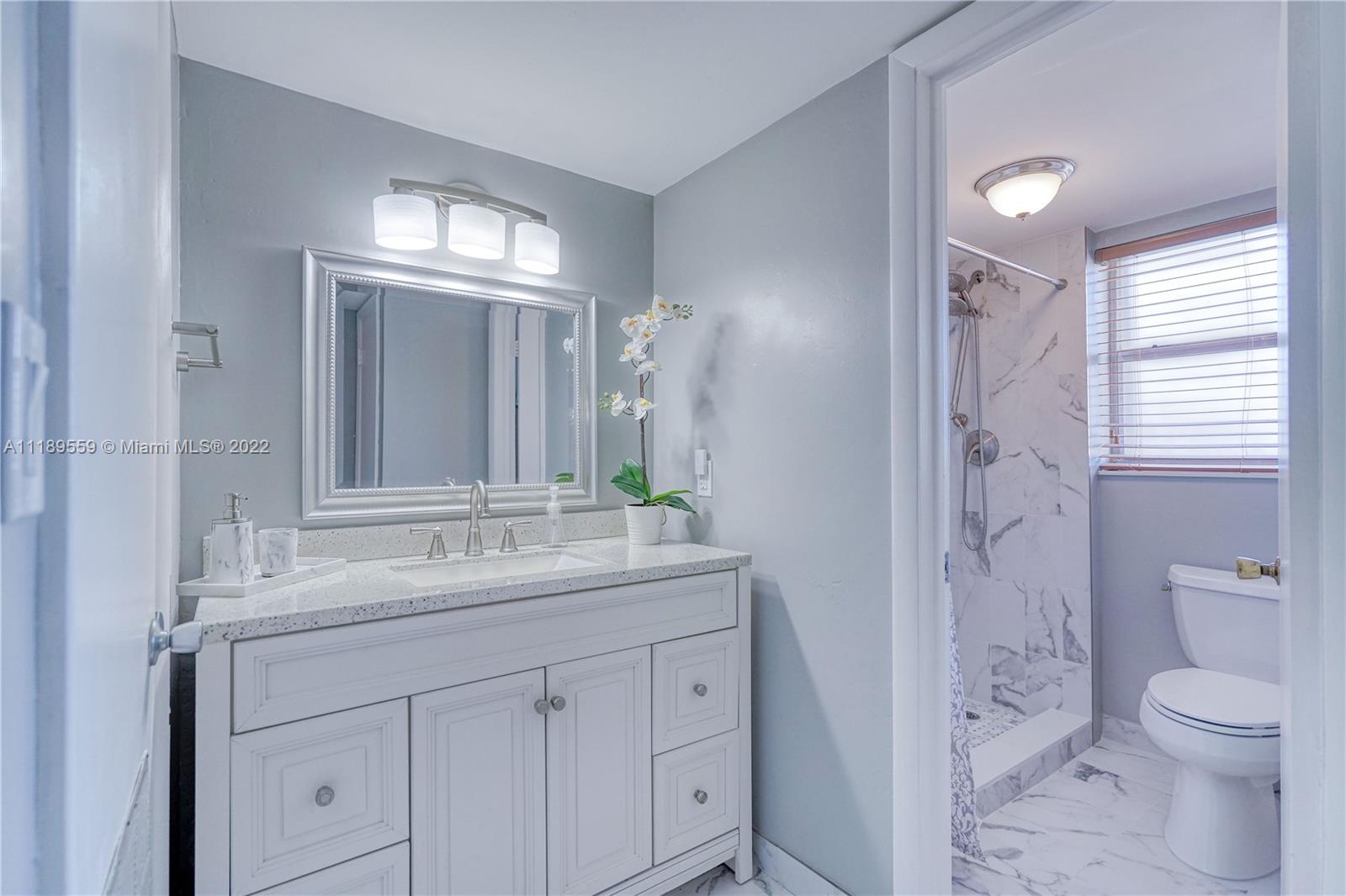 245 18th Street, Unit 602 Miami Beach, FL 33139 - Photo 21 of 40 a bathroom with a granite countertop sink a toilet and a large mirror