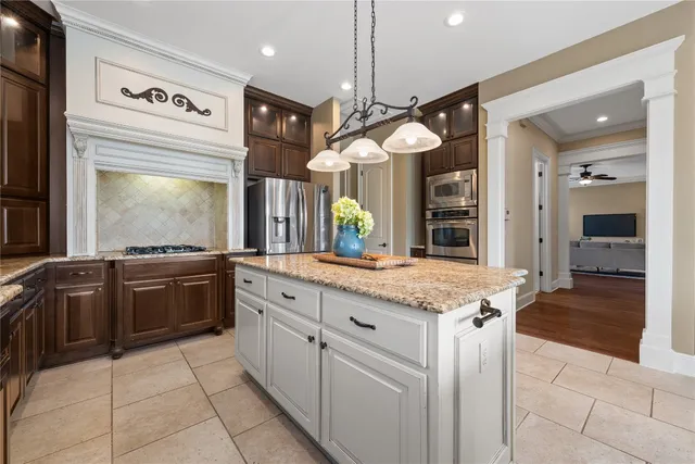 a large kitchen with granite countertop a large stove top oven and cabinets