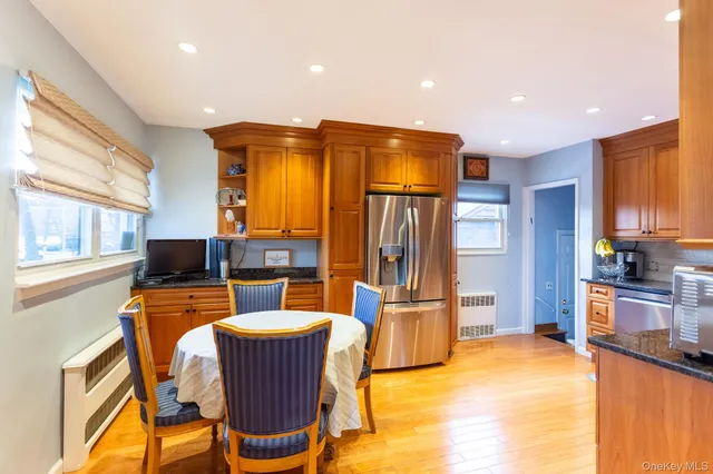 a kitchen with stainless steel appliances kitchen island granite countertop a refrigerator a stove top oven and a dining table with wooden floor