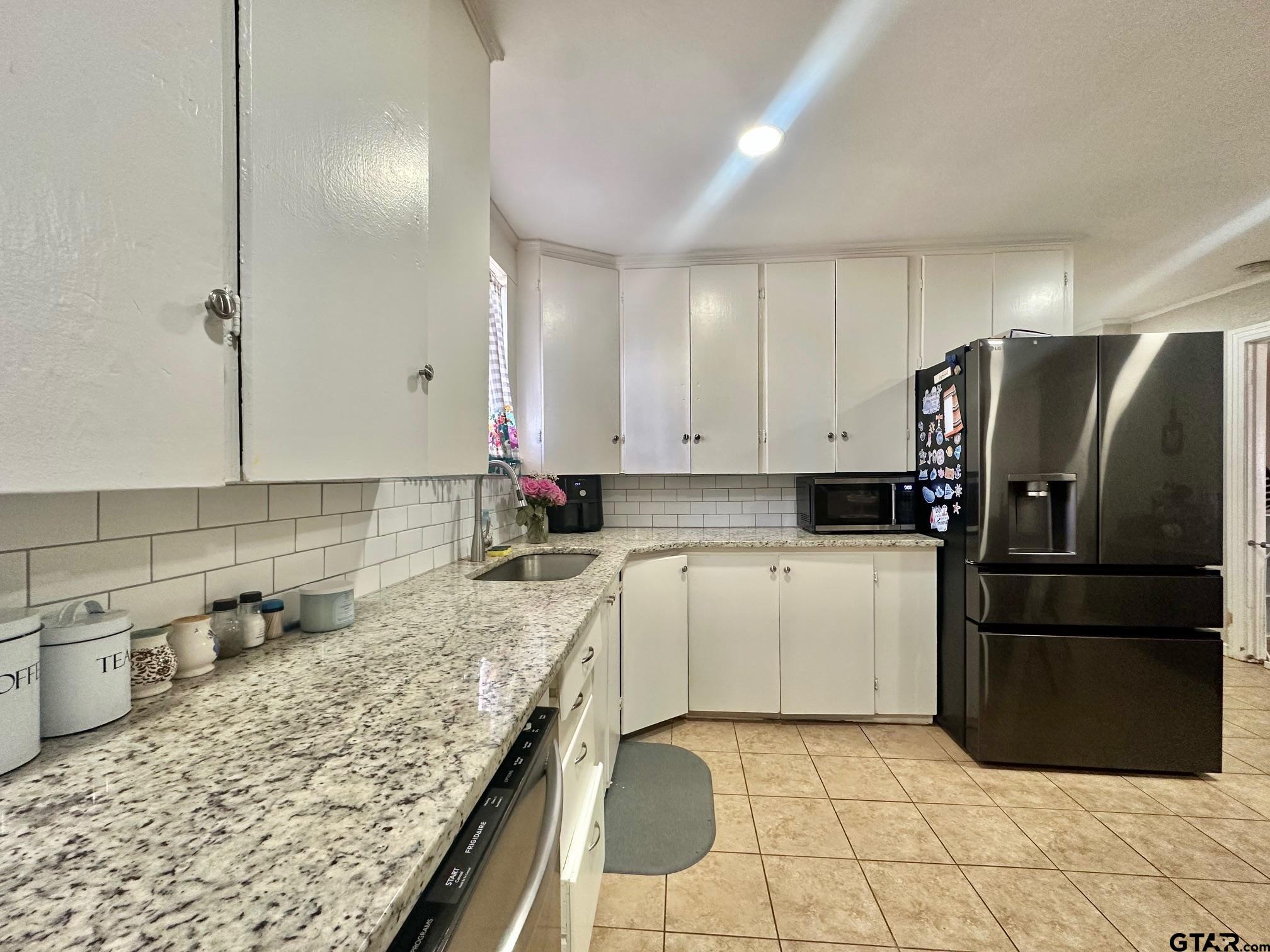 2601 East George Richey Road Longview, TX 75604 - Photo 17 of 26 a kitchen with a sink refrigerator and microwave