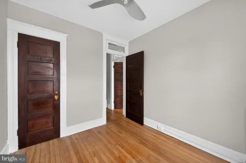 a view of empty room with wooden floor and fan
