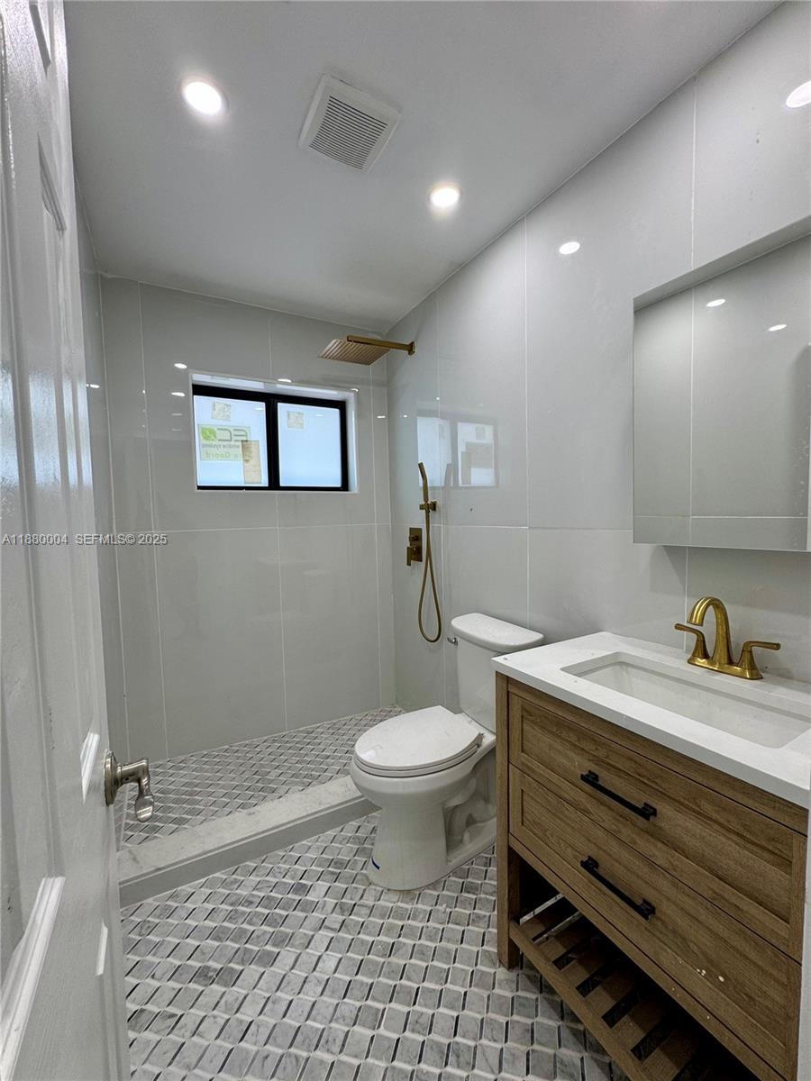 3030 Arthur Street Hollywood, FL 33021 - Photo 3 of 9 a bathroom with a granite countertop toilet a sink a mirror and vanity