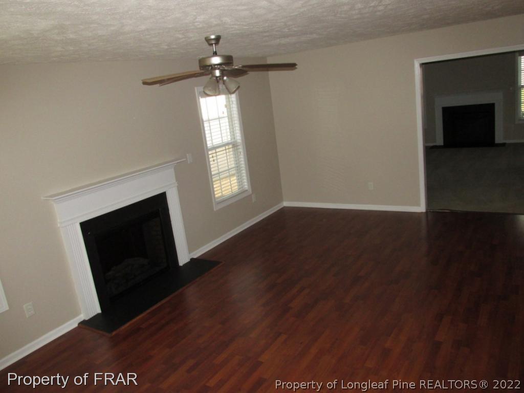 259 Cape Fear Road Raeford, NC 28376 - Photo 7 of 29 an empty room with wooden floor fireplace and windows