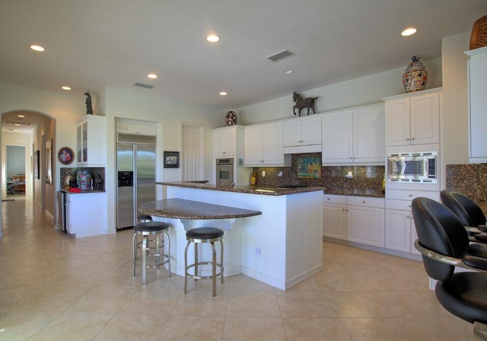 336 Loch Lomond Road Rancho Mirage, CA 92270 - Photo 11 of 26 a kitchen with stainless steel appliances kitchen island granite countertop a table chairs sink and cabinets