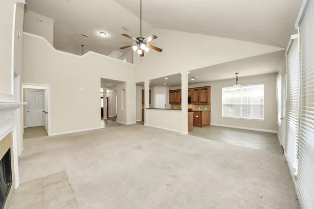 an empty room with chandelier fan and windows