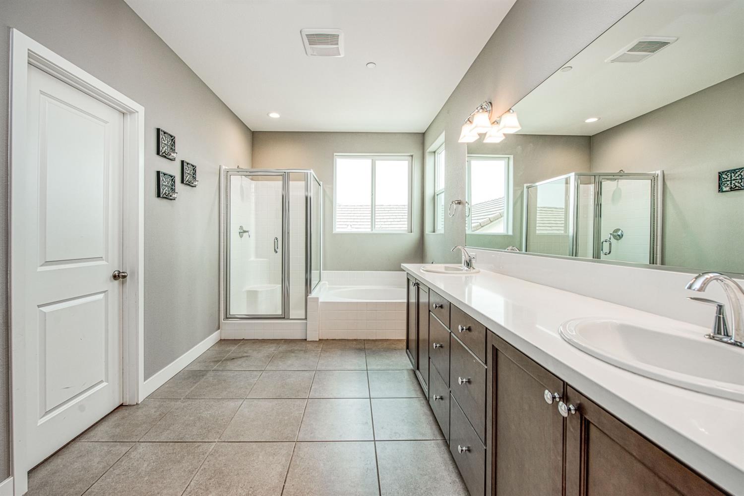 333 Meridian Avenue Madera, CA 93636 - Photo 32 of 38 a spacious bathroom with a double vanity sink a large mirror and a bathtub