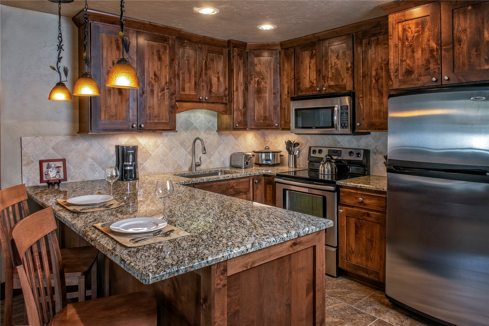 1979 Ski Hill Road, Unit COLORADO Breckenridge, CO 80424 - Photo 12 of 15 Kitchen featuring stainless steel appliances, a kitchen bar, a peninsula, dark stone countertops, and pendant lighting