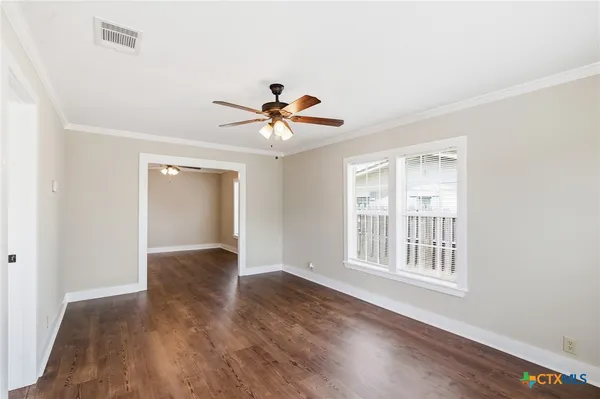 a view of an empty room with window and wooden floor