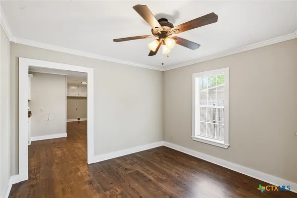 an empty room with wooden floor fan and windows