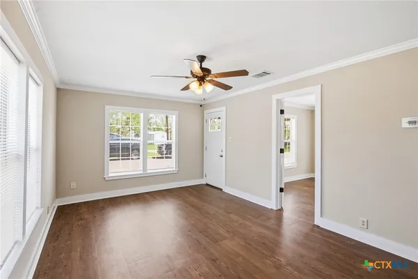 an empty room with wooden floor and windows