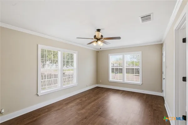 a view of an empty room with wooden floor and a window