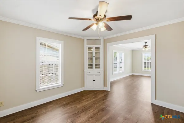 a view of an empty room with wooden floor and a window