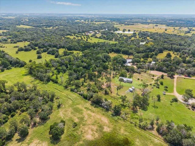 an aerial view of residential houses with outdoor space and trees