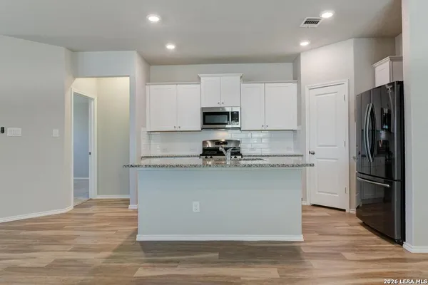 a kitchen with stainless steel appliances granite countertop a refrigerator and a stove top oven