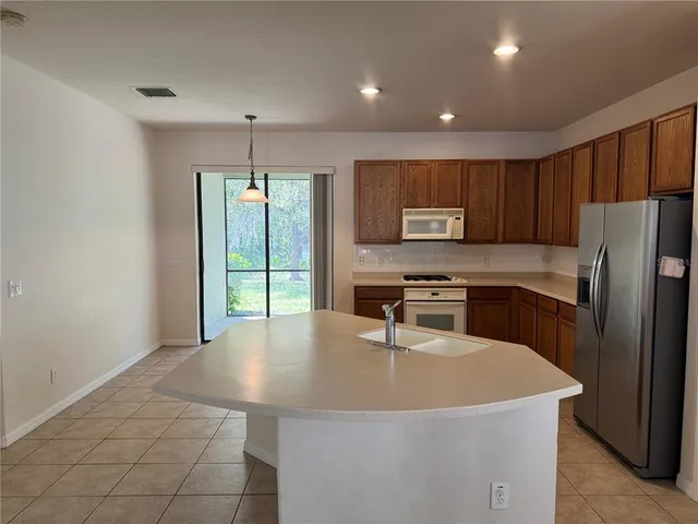 an empty room with wooden floor chandelier fan and windows