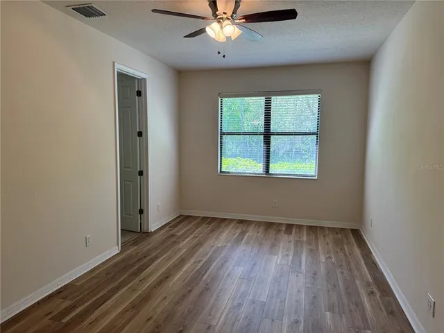 a view of a room with wooden floor and a ceiling fan