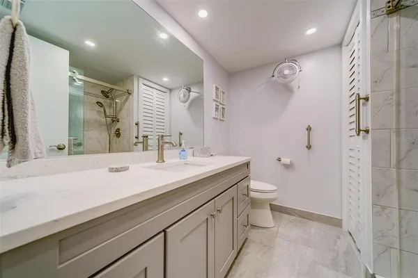 a bathroom with a sink a toilet a mirror and shower