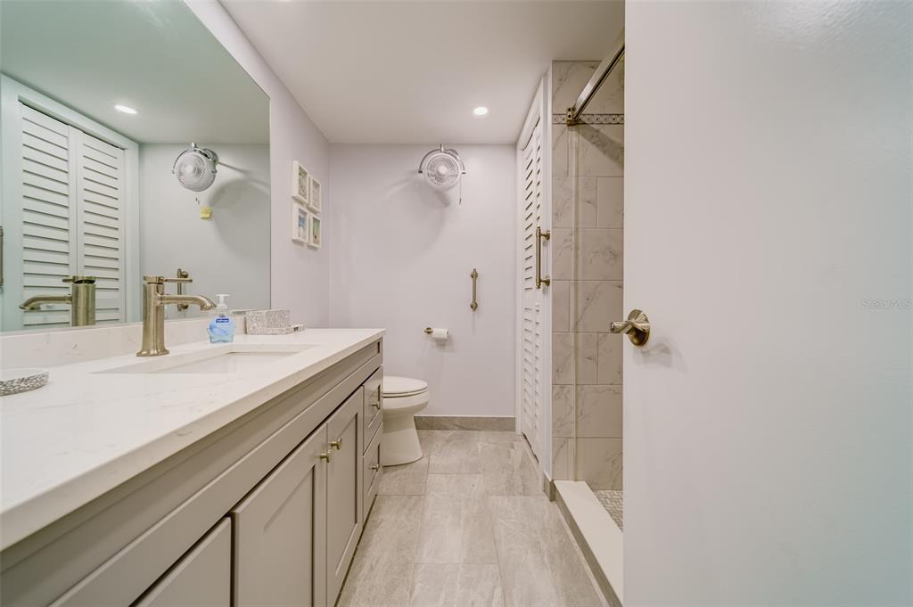 1 Windrush Boulevard, Unit 63 Indian Rocks Beach, FL 33785 - Photo 22 of 60 a bathroom with a sink a toilet a mirror and shower