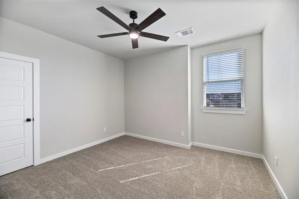 an empty room with a ceiling fan and a window
