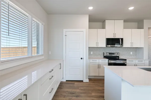 a kitchen with granite countertop white cabinets and stainless steel appliances