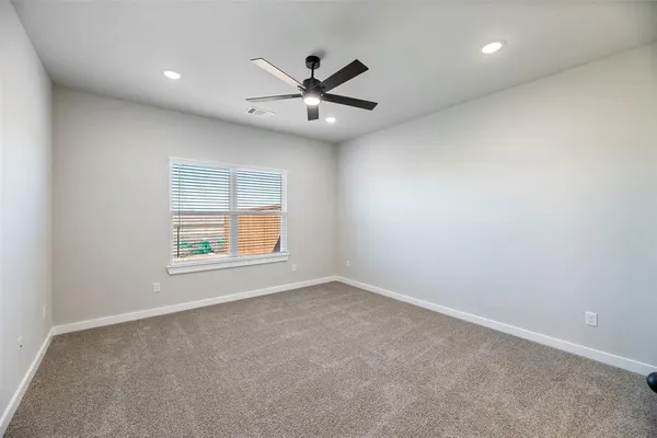 an empty room with windows and fan