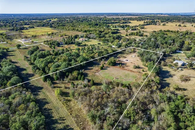 an aerial view of residential house with outdoor space and trees all around