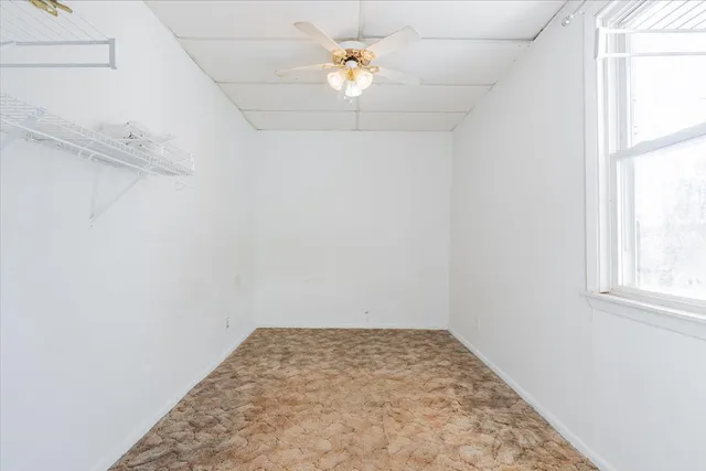an empty room with a window and a ceiling fan