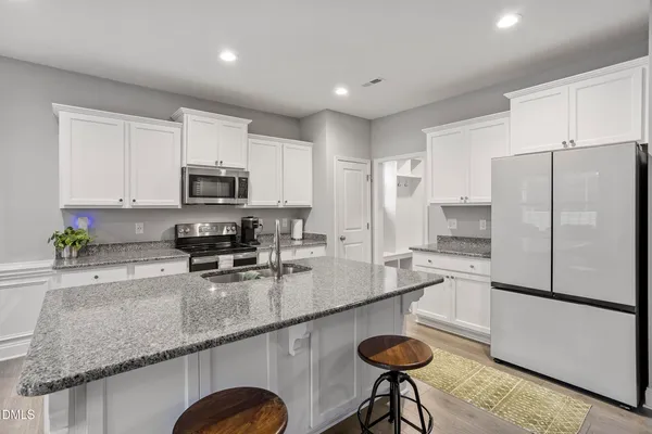 a kitchen with stainless steel appliances granite countertop a sink a stove a microwave a refrigerator and cabinets