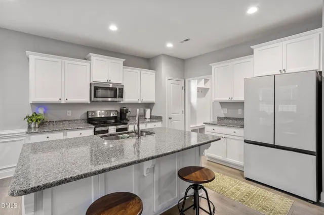 a kitchen with stainless steel appliances granite countertop a sink a stove a microwave a refrigerator and cabinets