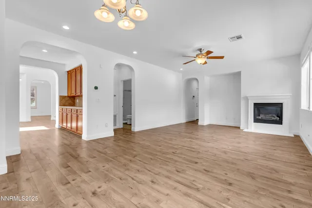 a kitchen with stainless steel appliances granite countertop a refrigerator a sink dishwasher a stove and a large window with wooden floor