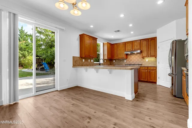 a kitchen with stainless steel appliances granite countertop a refrigerator a stove and a sink with wooden floor