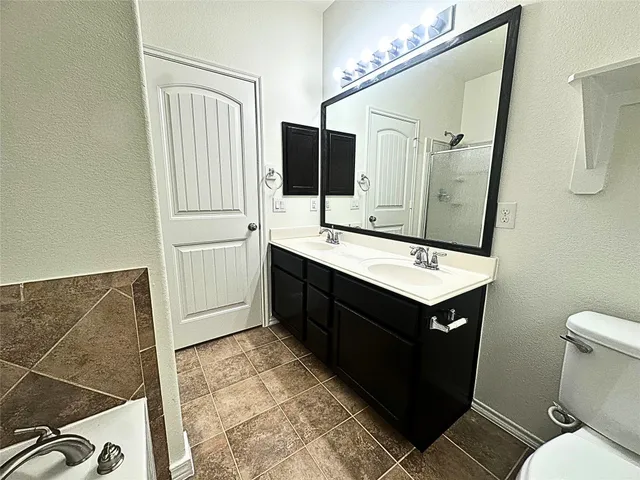 a bathroom with a sink vanity granite toilet and a mirror