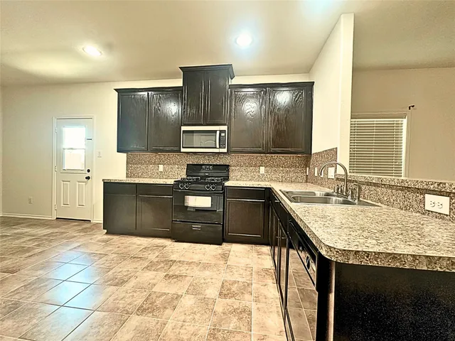 a large kitchen with granite countertop a sink and cabinets