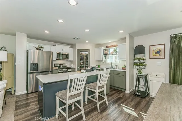 a kitchen with stainless steel appliances a dining table chairs refrigerator and cabinets
