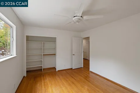 a view of an empty room with a window and wooden floor