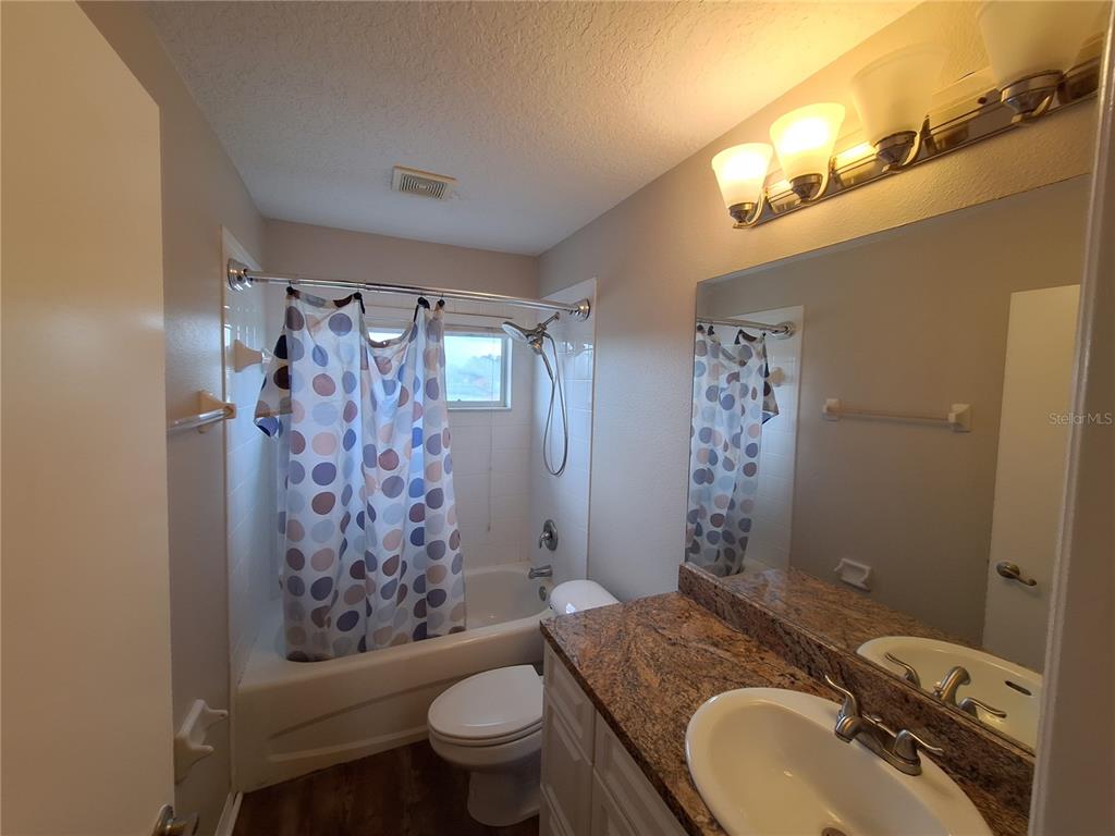 27854 Breakers Drive Zephyrhills, FL 33544 - Photo 15 of 16 a bathroom with a granite countertop toilet a sink a shower curtain and a large mirror