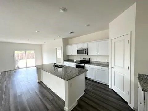 a kitchen with kitchen island granite countertop a sink cabinets and wooden floor