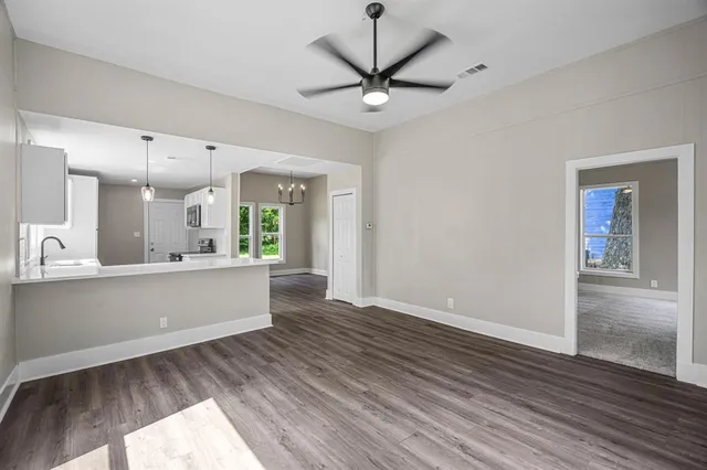 a living room with wooden floor and a ceiling fan