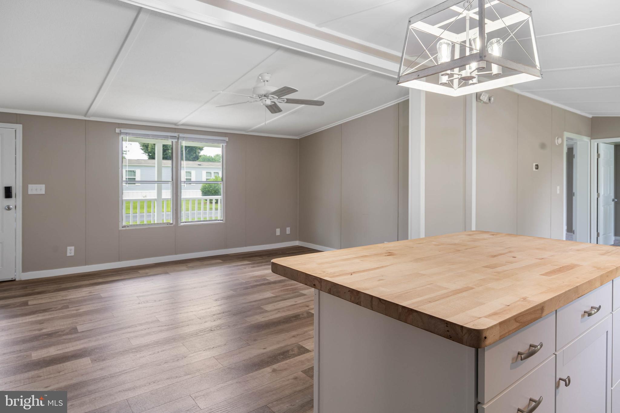 31392 Oak Street Ocean View, DE 19970 - Photo 15 of 38 a hall with kitchen island stainless steel appliances wooden floor wooden floors and a chandelier