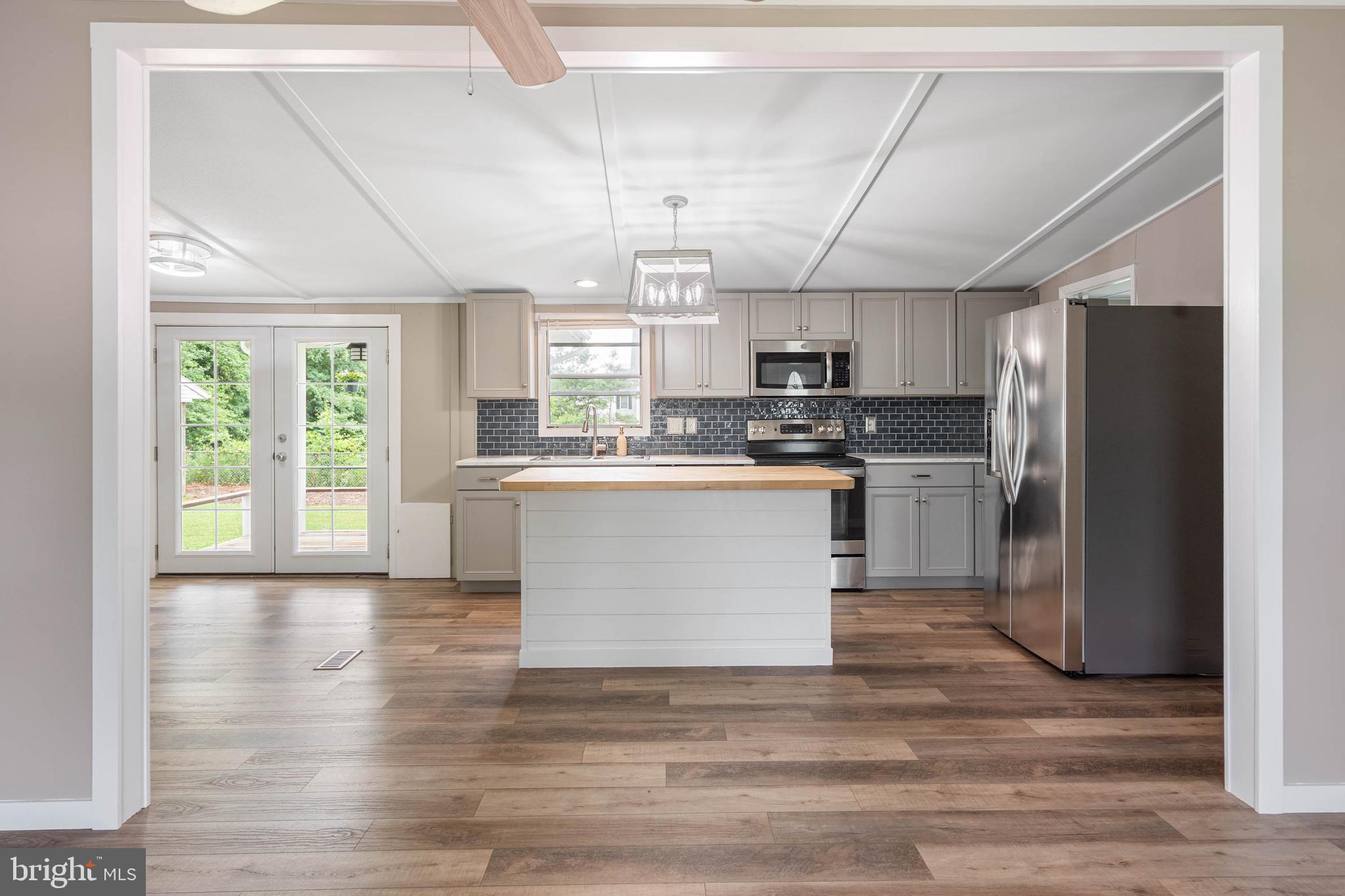 31392 Oak Street Ocean View, DE 19970 - Photo 9 of 38 a kitchen with stainless steel appliances a refrigerator a sink dishwasher a stove a microwave oven and a dining table with wooden floor