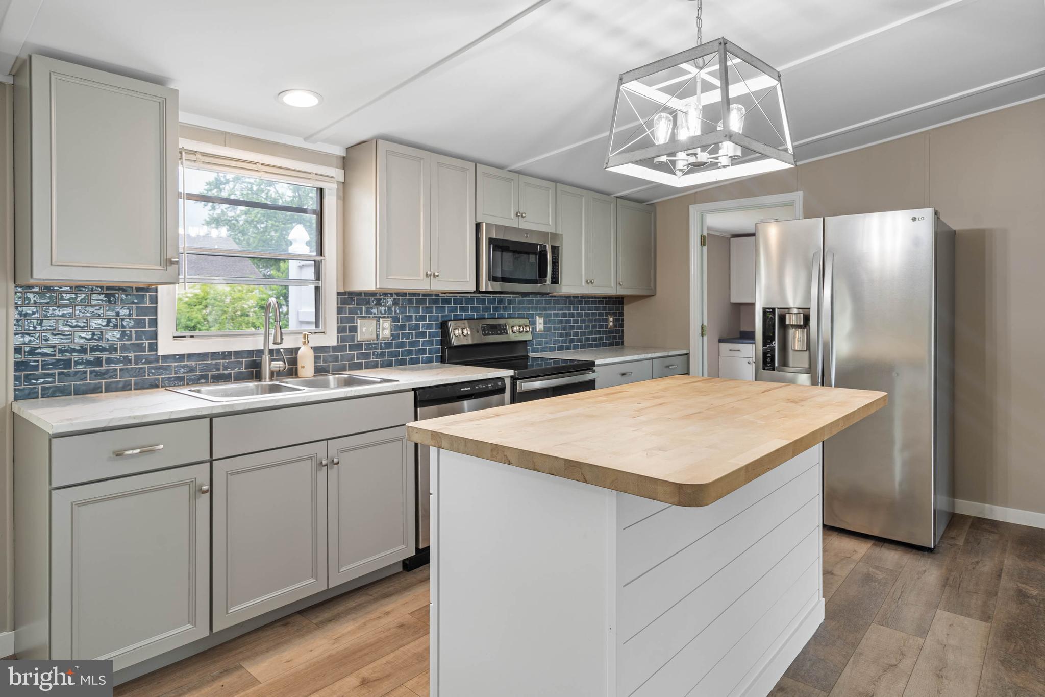 31392 Oak Street Ocean View, DE 19970 - Photo 10 of 38 a kitchen with stainless steel appliances granite countertop a sink dishwasher a refrigerator and a stove with wooden floor