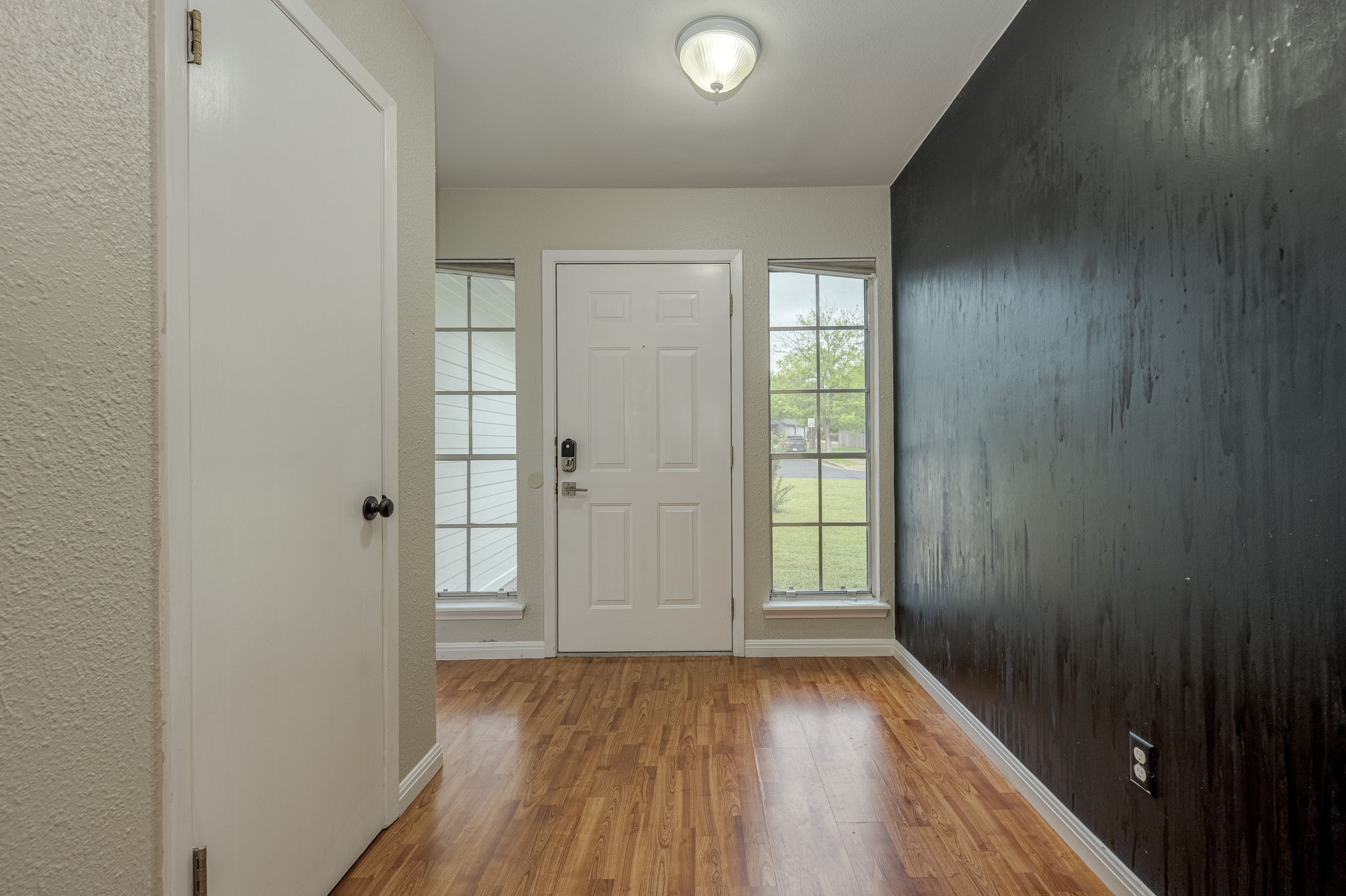 4815 Transit Circle Austin, TX 78727 - Photo 5 of 35 Welcoming entryway featuring wood-look flooring, a paneled front door with side windows, and a fun chalk accent wall full of personality.