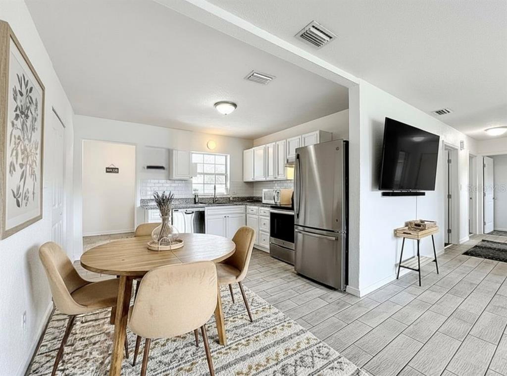 216 Obrien Road Casselberry, FL 32730 - Photo 8 of 22 a kitchen with stainless steel appliances kitchen island granite countertop a dining table chairs and a refrigerator