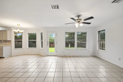 a view of an empty room with a window and kitchen view