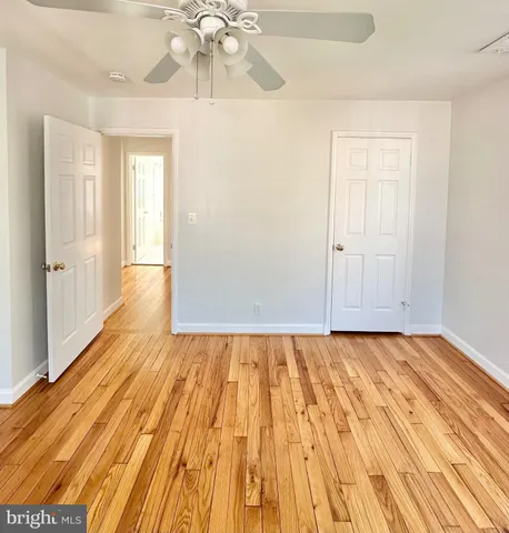 a view of an empty room with wooden floor and a chandelier fan