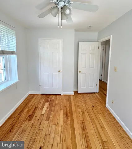 a view of an empty room with wooden floor and window