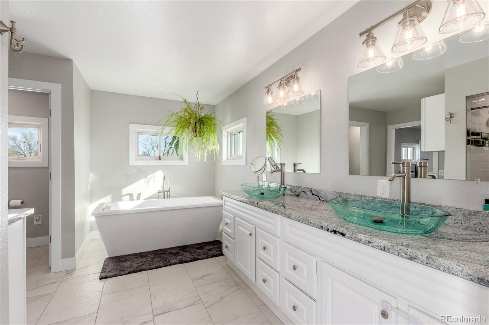 15528 Nancy Avenue Fort Lupton, CO 80621 - Photo 14 of 35 a spacious en suite bathroom with a granite countertop sink and a mirror